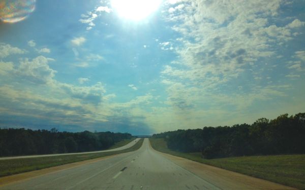 View of sky through dashboard of car on highway